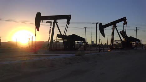 oil derricks pump against the sunset