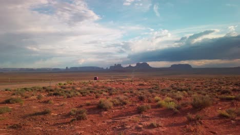 static wide shot of monument valley with a van driving towards it