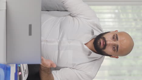 vertical video of home office worker man shocked by what he reads and sees.