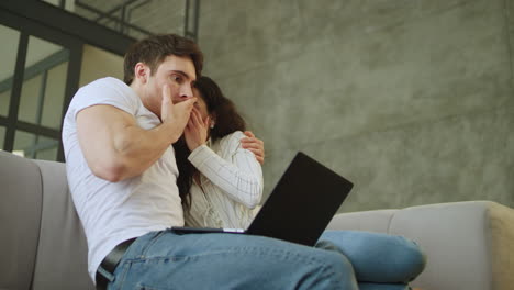 portrait of scared couple watching laptop computer at home in slow motion.