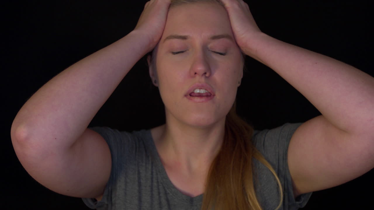 Young woman is despairing. The woman cries about her problems, raises her hands to her forehead. She is upset. The woman is depressed