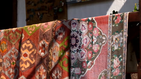 beautiful old blankets hanging on a wooden banister to dry outside a home in yuriy gyumri, armenia - wide pan shot