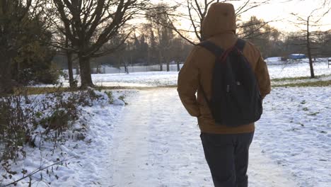 caucasina male walking alone on snow park forest during winter xmas holiday season wearing modern trendy orange jacket