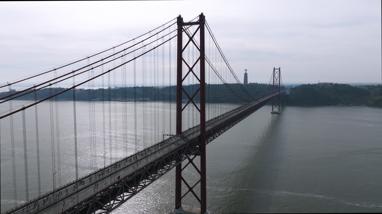 Half marathon and 10K long distance running event in Lisbon, Portugal, Europe. Runners crossing the iconic famous red 25th April suspension bridge by Cristo Rei. Tagus river panorama