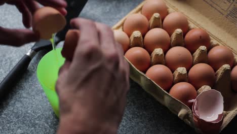 breaking several eggs after which the egg yolk and egg white end up in a green plastic cup.