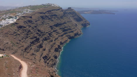 Toma-Aérea-Lenta-Y-Reveladora-De-La-Roca-Skaros-En-Santorini,-Grecia-Durante-Un-Día-Soleado