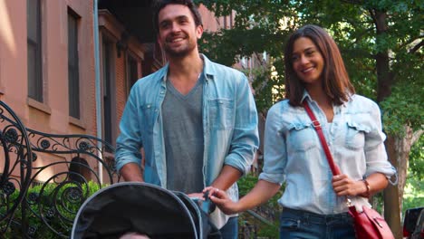 Happy-couple-walking-in-the-street-with-baby-in-a-stroller