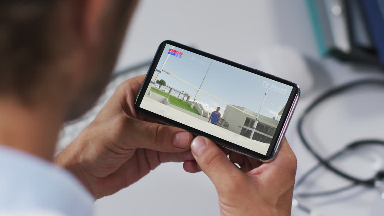 compuesto de un médico masculino viendo un evento de salto de altura en el teléfono inteligente