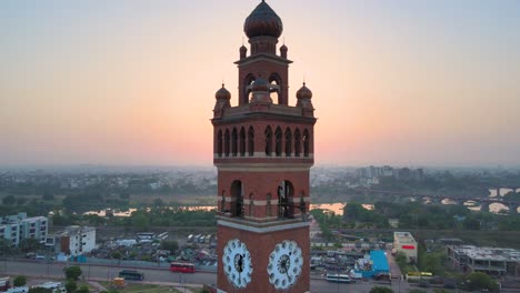 una toma aérea de la torre del reloj de lucknow, con el sol saliendo detrás de ella, creando una silueta.