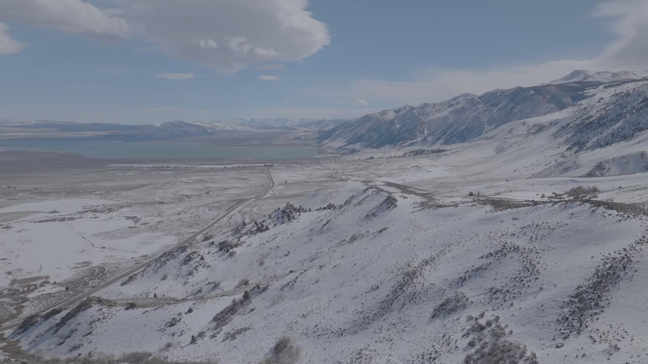Aerial view of Lake Tahoe's snow-covered mountains and pine forest. Bright winter day with blue sky. 4K drone cinematography capturing pristine alpine wilderness and forested mountain slopes