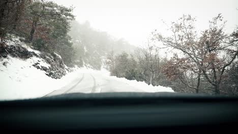 겨울에 산 숲에서 눈 덮인 도로를 운전, 앞 유리보기