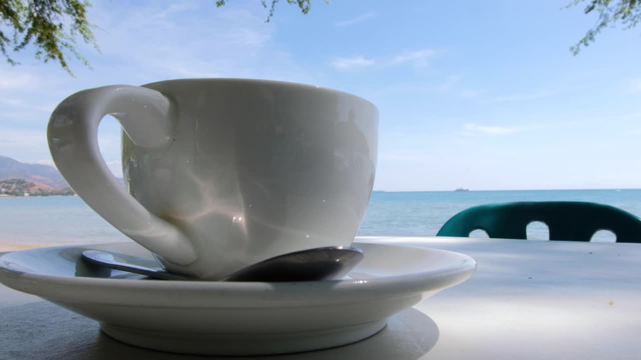 una taza de café en una mesa exterior en la playa con vistas al océano en una isla tropical en timor leste, sudeste de asia
