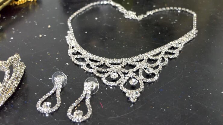 colpo del primo piano della borsa della donna, della borsa, della collana, dell'anello di orecchio e degli accessori di nozze