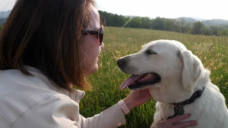 Woman-plays-with-white-lab-dog-with-mountain-backdrop