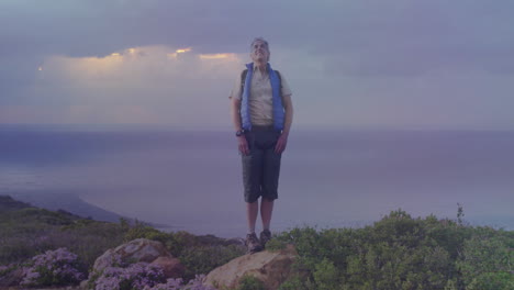 man standing on rocky coastal cliff overlooking ocean at dusk, showing animated tech icons and data