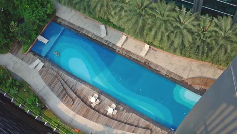 Aerial-View-Of-Man-Swimming-In-The-Pool-Enjoying-Vacations-In-Tropical-Destination