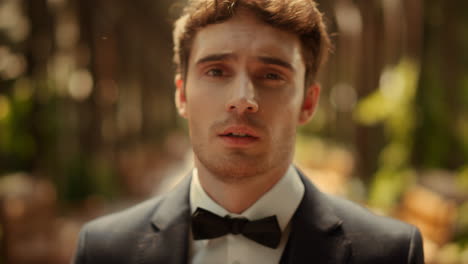 Sensual-man-posing-in-garden-before-wedding.-Groom-turning-head-right-under-arch