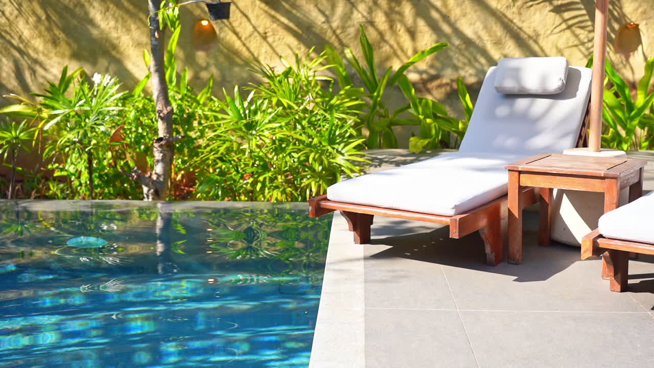 Eine leere Strandliege steht am Rande eines kleinen privaten Pools.