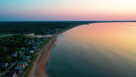 aerial drone view of beautiful beach houses and sunset over maine vacation homes and colors reflecting off ocean waves along the new england atlantic coastline