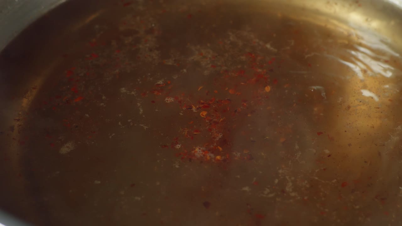 Close Up Of Chili Being Sprinkled Into The Boiling Soup Pot. Sukiyaki Or Shabu