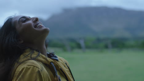 independent young indian woman looking up smiling happy enjoying gentle rain travel adventure alone in peaceful countryside