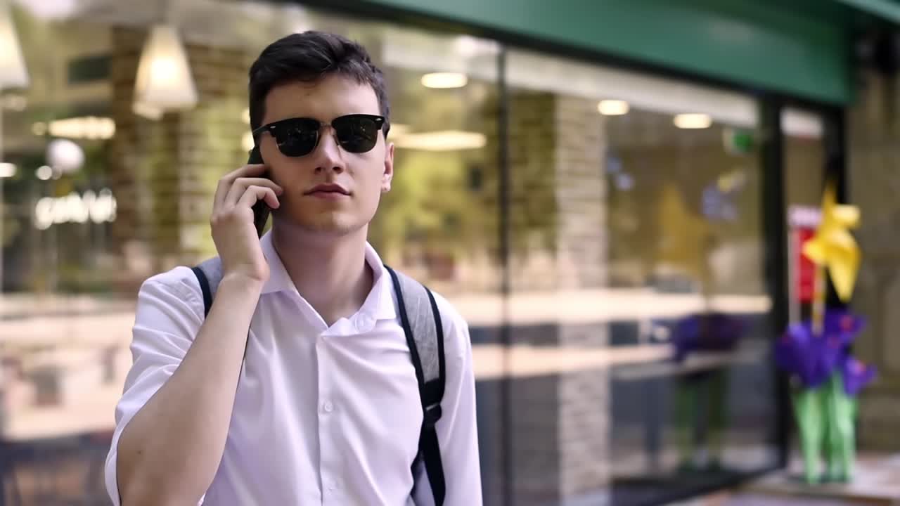 Caucasian man in white shirt and sunglasses talking on the phone. Sunny day