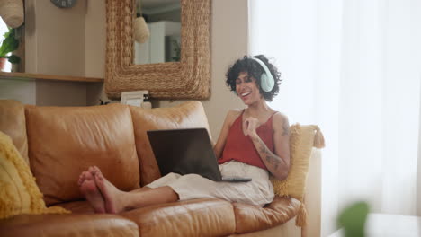 mujer relajándose en el sofá con computadora portátil y auriculares
