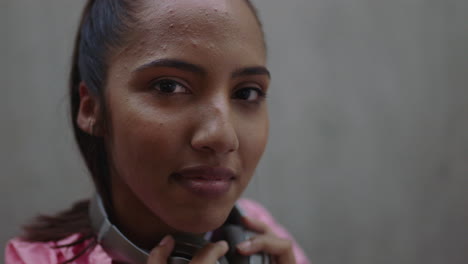 Primer-Plano-Retrato-Hermosa-Joven-Mujer-De-Raza-Mixta-Mirando-Confiada-A-La-Cámara-Sosteniendo-Auriculares