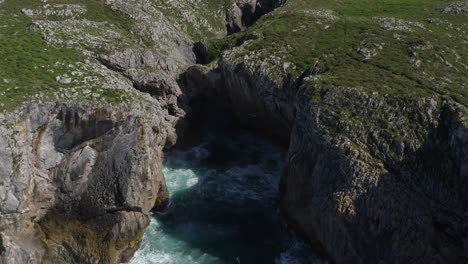 bufones-de-pria-asturias-spain-erosion-cavern,-aerial-dolly-tilt-down-top-down-view