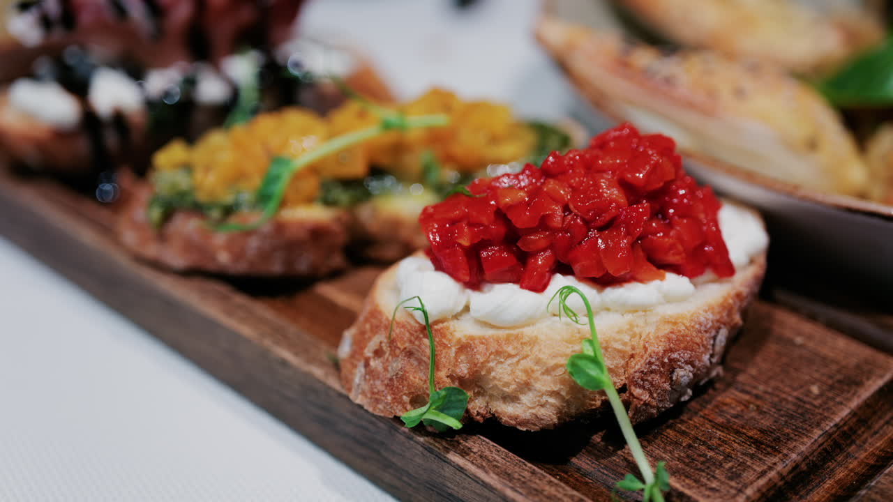 Close up of rustic bruschetta topped with cream cheese and roasted red peppers, garnished with fresh greens