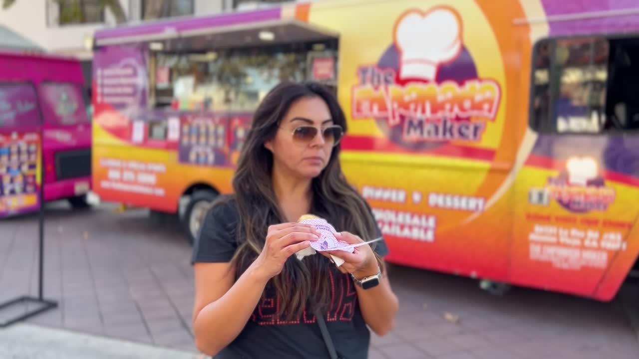 atractiva mujer latina comiendo un bocadillo comprado en un camión de comida