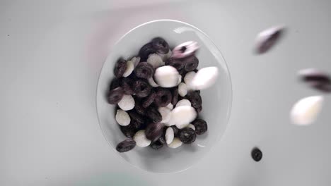 bird's eye view of cereals flying into bowl on white table, vertical shot