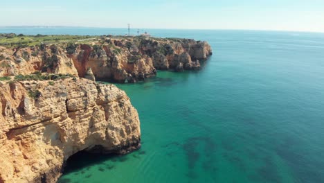 Farol-Ponta-da-Piedade,-lighthouse-overlooking-the-Atlantic-Ocean-emerald-waters,-Lagos,-Algarve