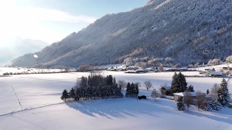 river covered with snow near the village during winter season near the mountain, aerial ascending