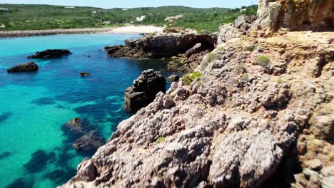 flying through rugged and rocky cliffs by the blue sea. - aerial shot
