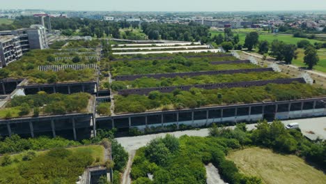 aerial - overgrown industrial ruins near zagreb croatia beside fields and scattered vehicles