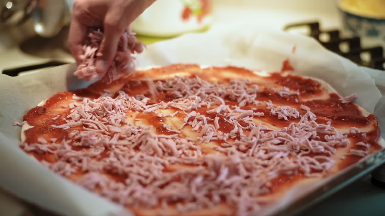 Female hands adding sliced sausages into a raw pizza. Slow motion
