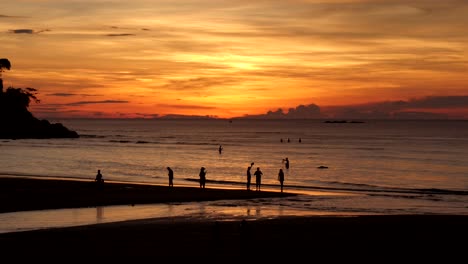 Grupo-De-Personas-En-Una-Playa-Con-Una-Hermosa-Puesta-De-Sol