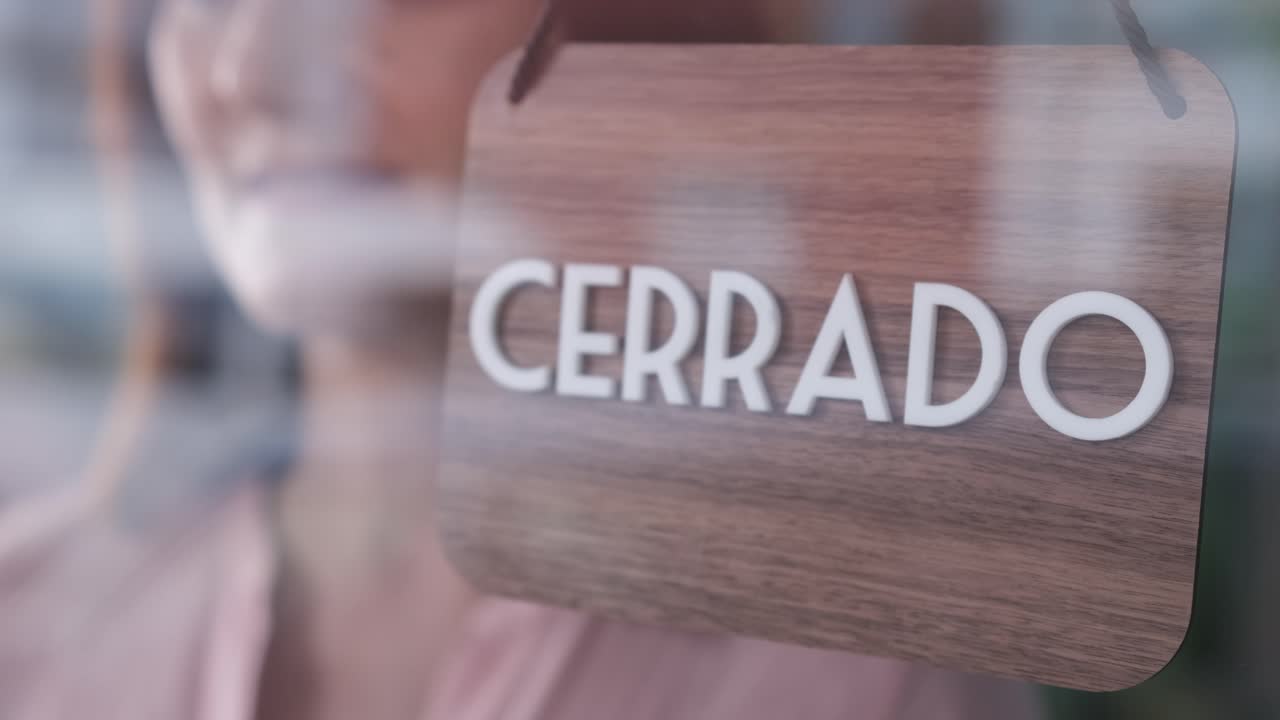 Happy woman changing closed to open sign in spanish, unrecognizable. Start-up concept. 4k 60fps