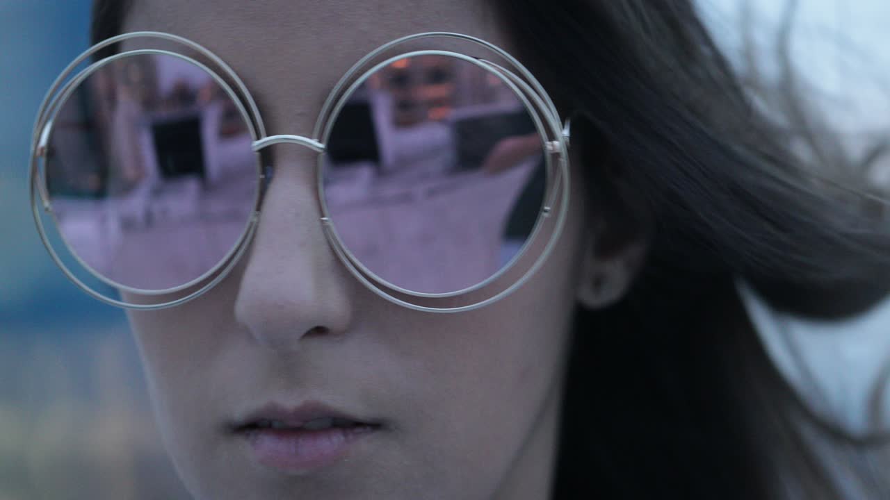 chica posando con gafas de sol grandes y redondas por la noche