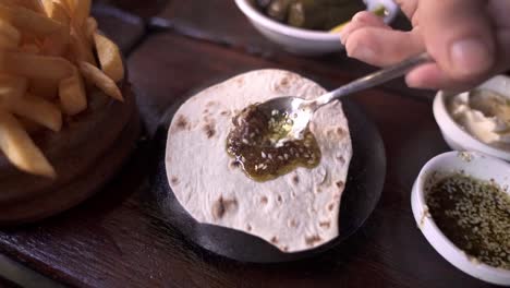 Gesichtsloser-Mann,-Der-In-Einem-Orientalischen-Restaurant-Zaatar-Sauce-Auf-Fladenbrot-Aufträgt