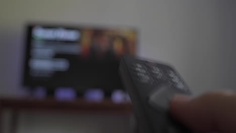 person using remote to sift through shows on tv