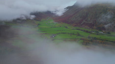 Volando-Sobre-Nubes-Bajas-Con-Revelación-De-Valle-Verde-Rodeado-De-Montañas-Envueltas-Por-Nubes