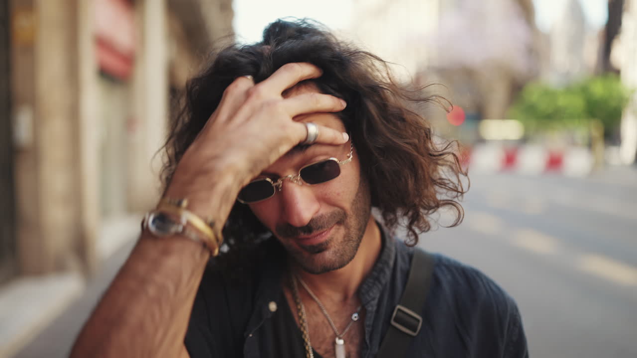 Man with Curly Hair Wearing Sunglasses on City Street