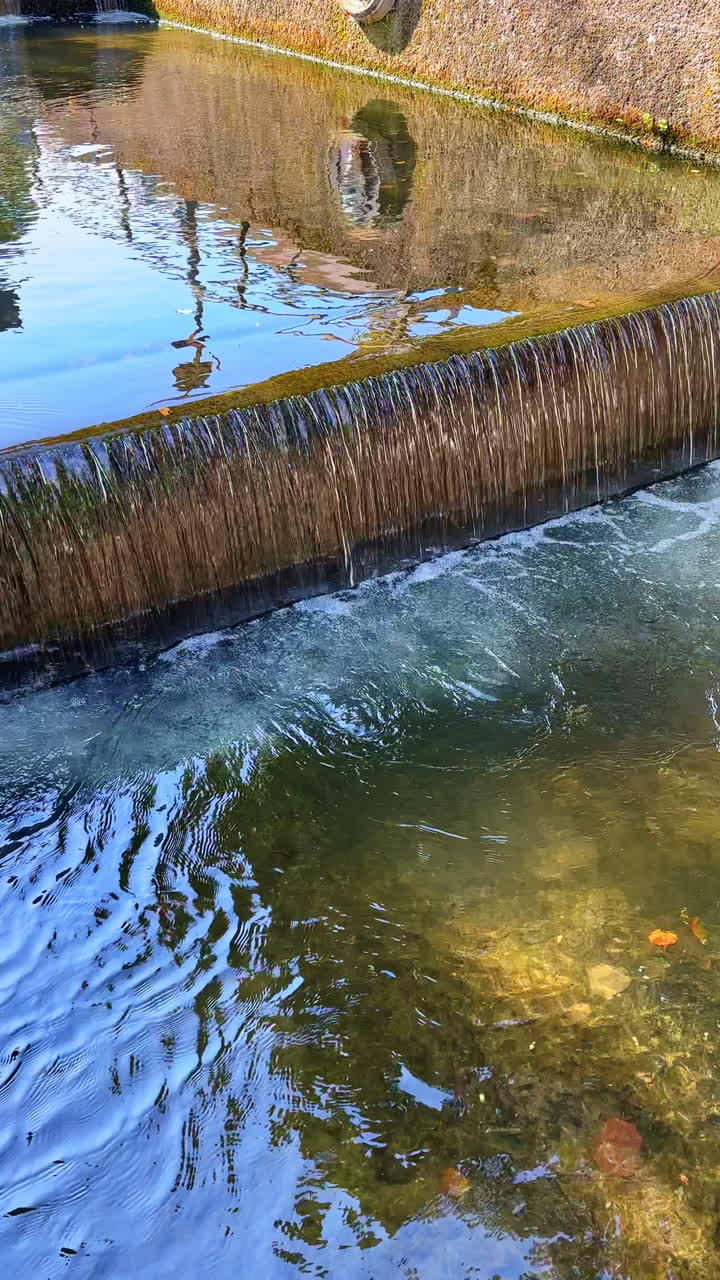 Água borbulhante flui suavemente sobre rochas num cenário natural sereno sob um céu azul claro