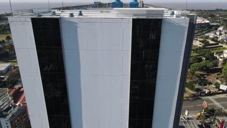 Aerial-tilt-up-shot-of-modern-gigantic-building-tower-in-Buenos-Aires-City-against-blue-sky-and-sunlight