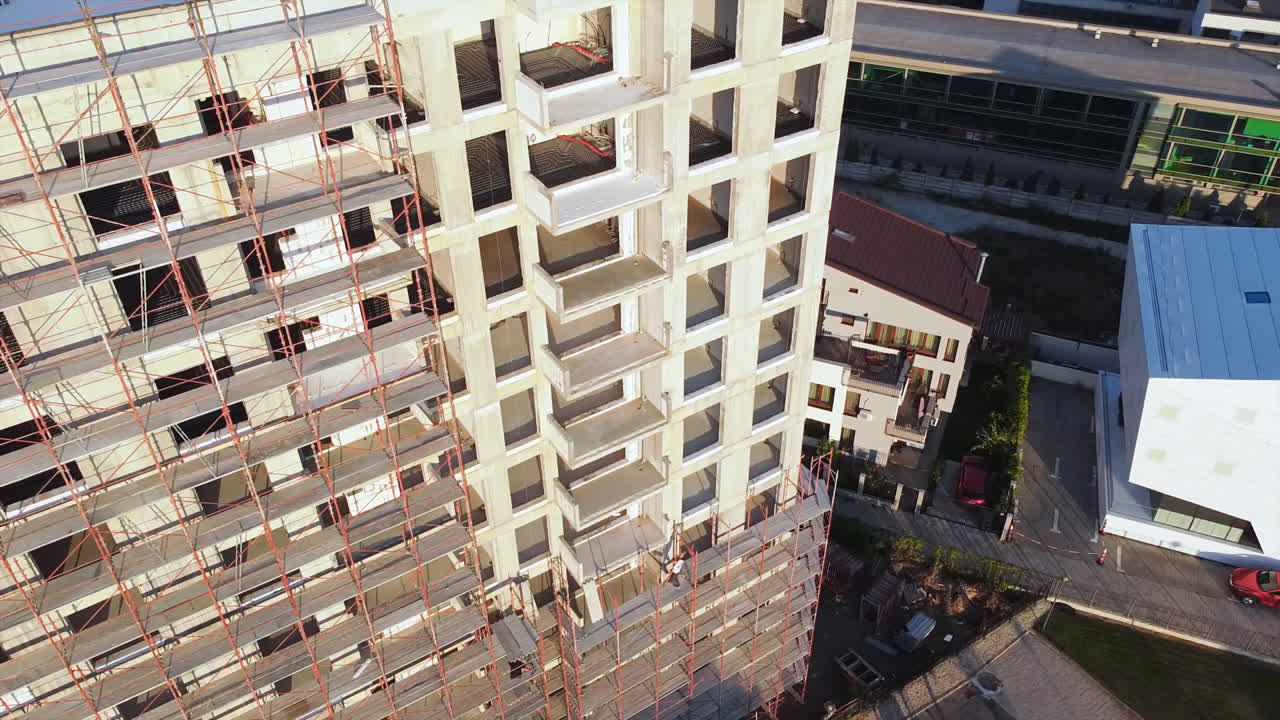 Construction works of a building with scaffolding on the facade. View from the drone. Bucharest, Romania