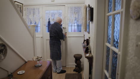 an elderly man opening the door inside his home