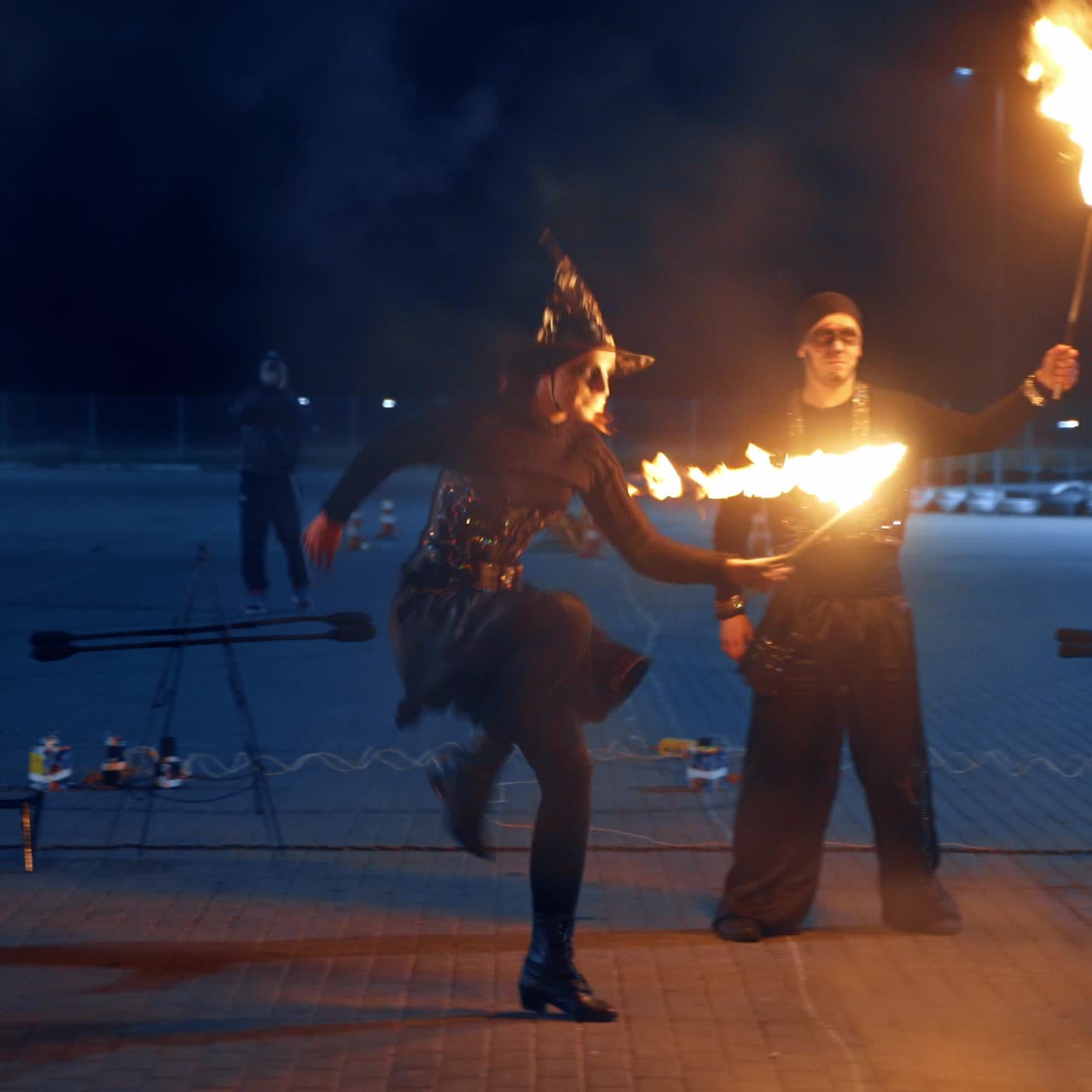 Dos hombres y dos mujeres bailan con antorchas encendidas. Un grupo de artistas realiza un espectáculo de fuego al aire libre.