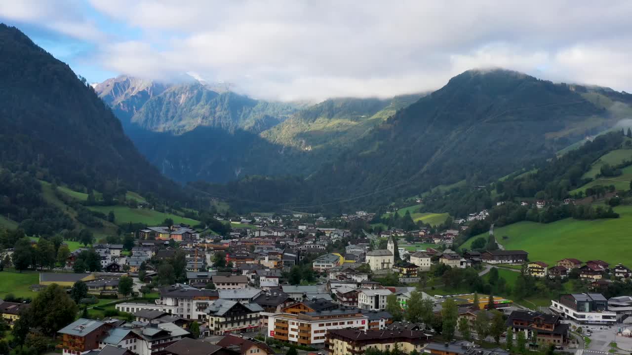 vista aérea del pueblo austriaco rodeado de montañas durante el verano, exuberantes colinas verdes y cielo azul - panorama paisajístico de los alpes desde arriba, austria, europa